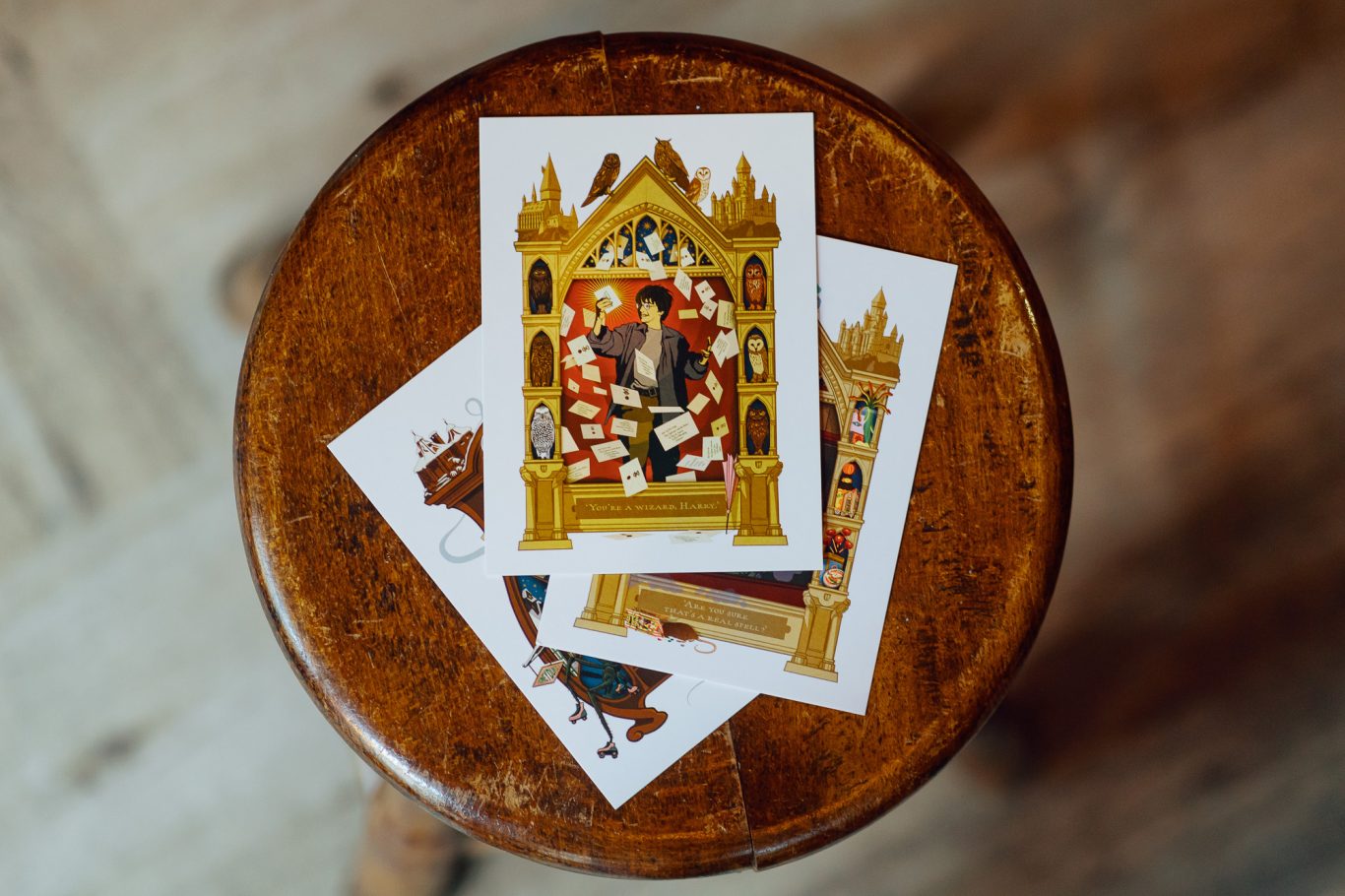 Magical Moments Postkarten Postkarten mit historischen Motiven auf einem runden Holzschemel.